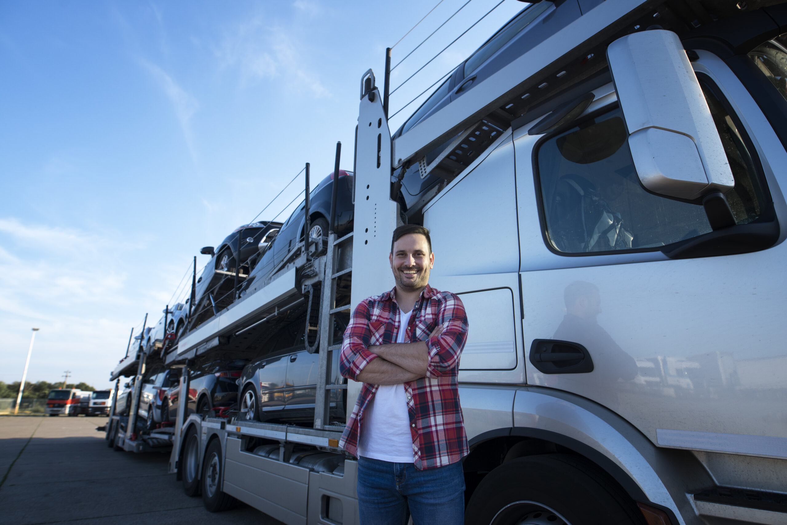 Proteção Veicular Caminhão - portrait professional smiling truck driver with crossed arms transporting cars market scaled